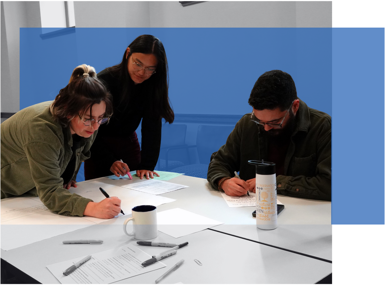 Three young professionals collaborate at a table during a Civic Design Workshop.