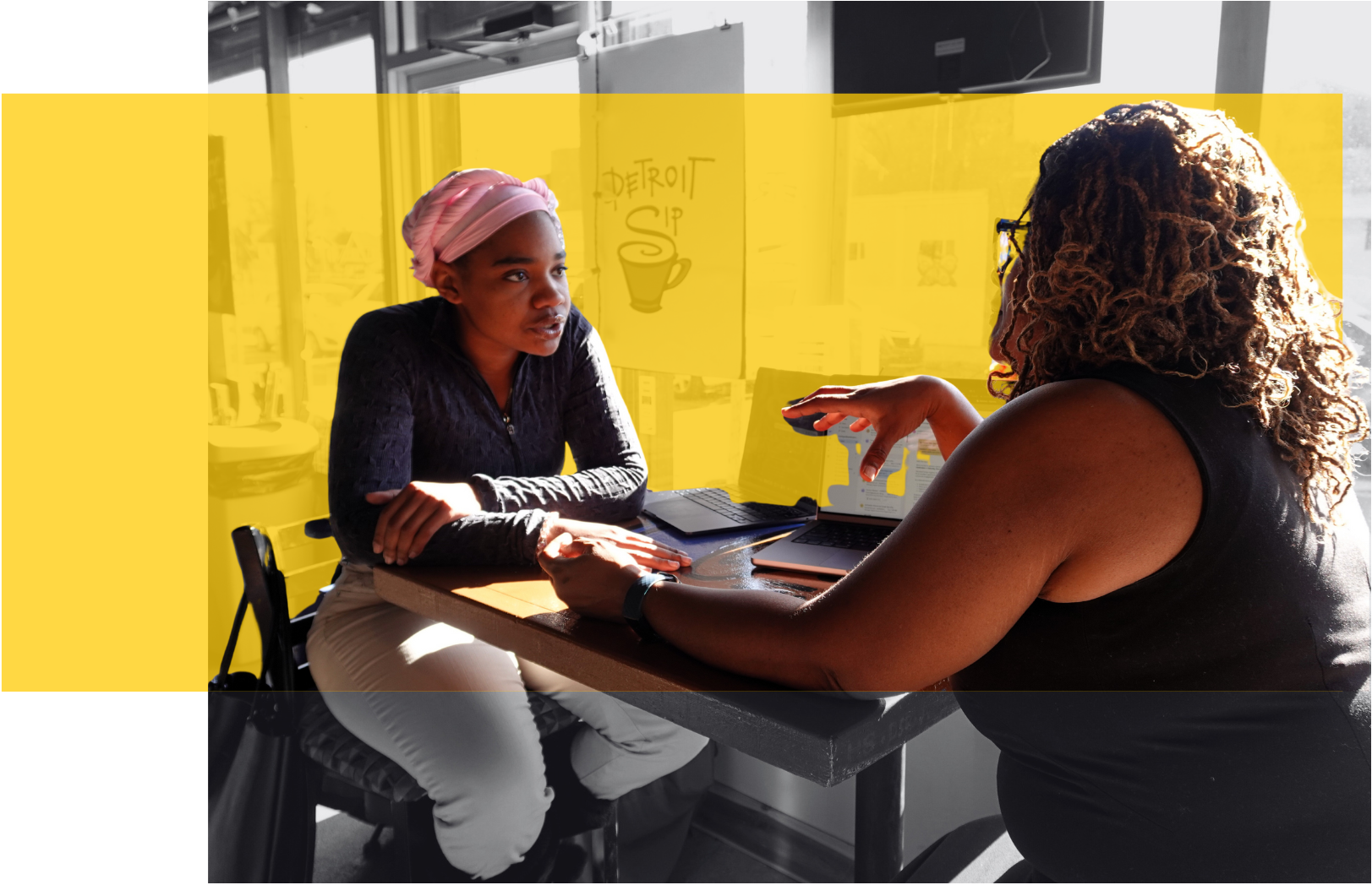 Two women collaborating in a café with a yellow graphic overlay.