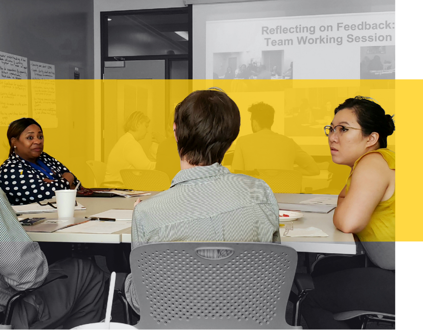 A group of people engaged in a meeting around a white table.