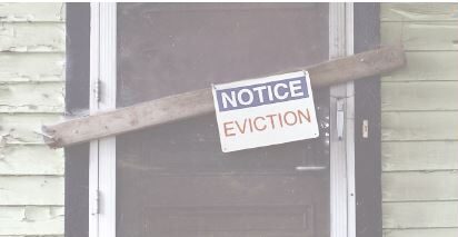 Eviction notice posted on a boarded-up door.