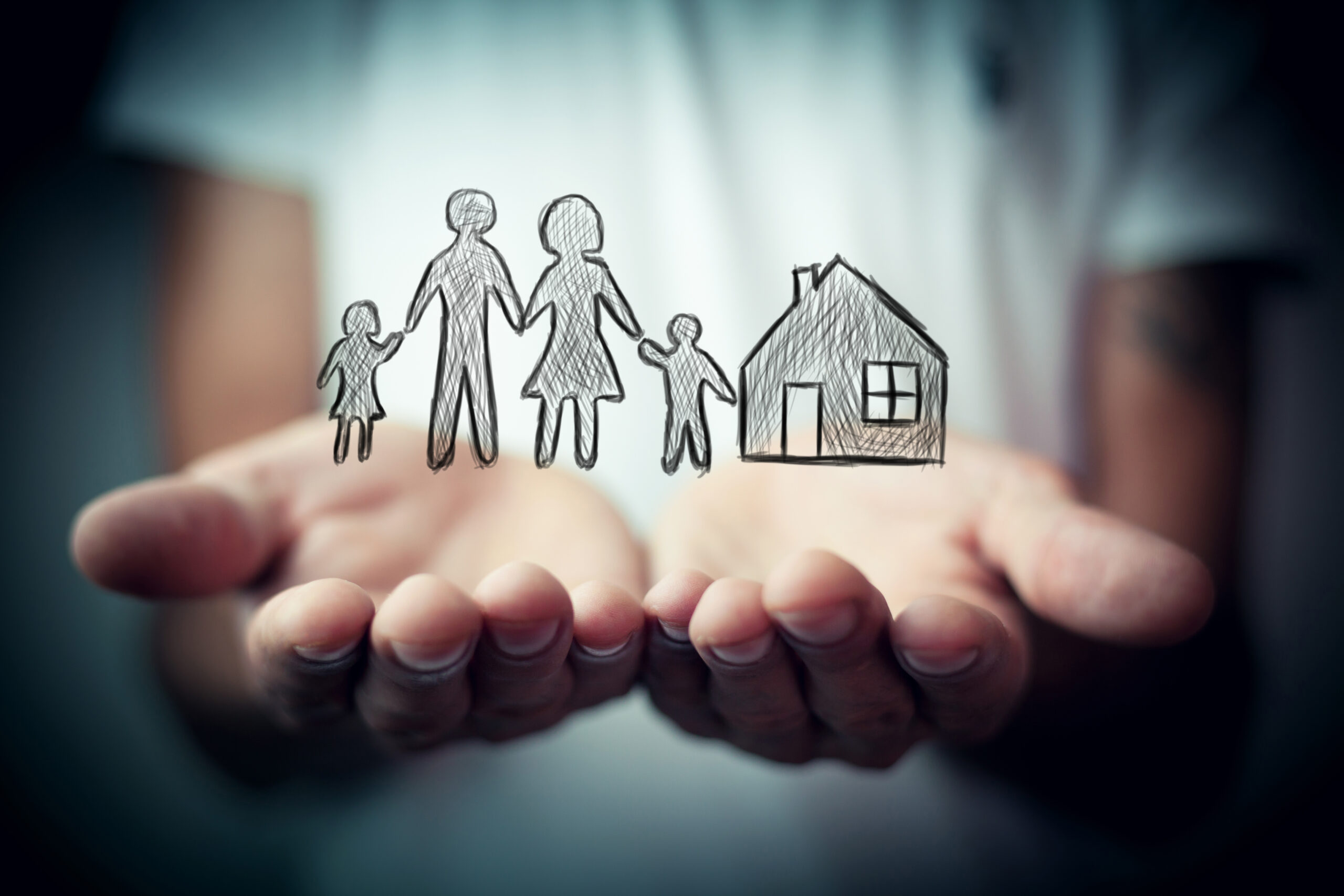 Kid's hand holding an illustration of a family and a house