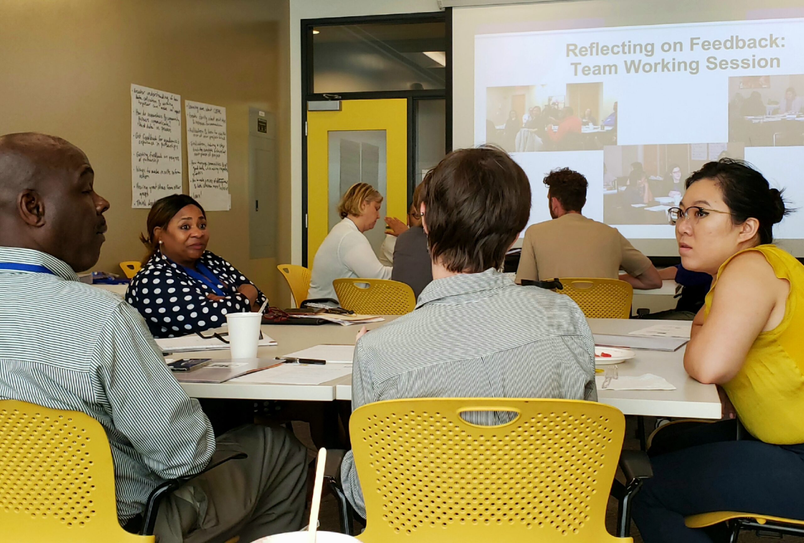 A table of participants engaging in a Reflecting on Feedback team working session.