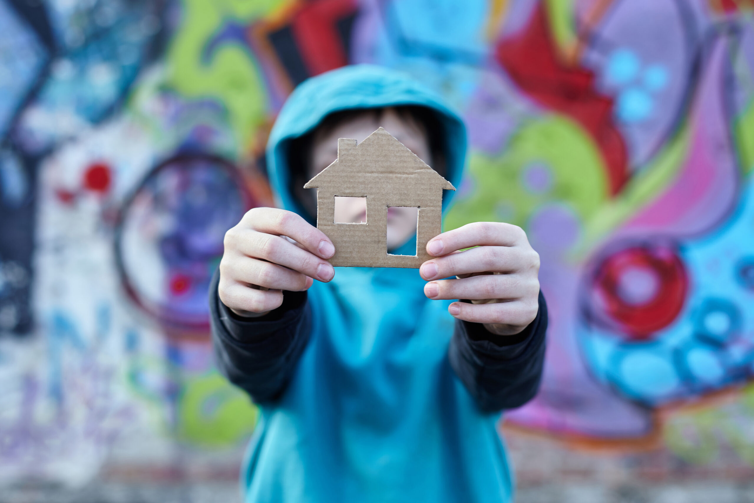 Young Homeless Boy Holding A Cardboard House