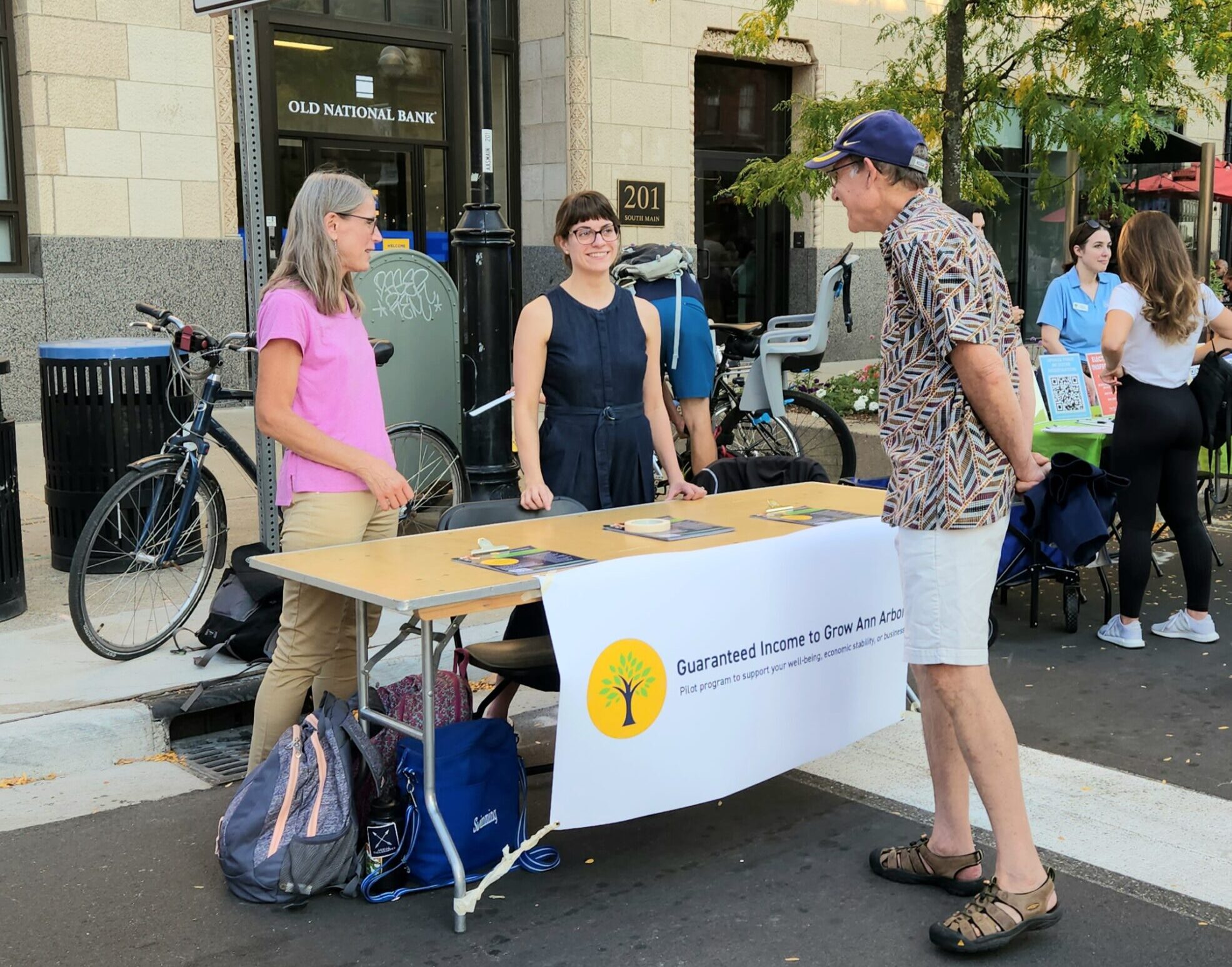 Poverty Solutions Associate Faculty Director Kristin Seefeldt (left) and Graduate Student Research Assistant Emily Shupp Parker (center) share information on Guaranteed Income to Grow Ann Arbor at the Green Fair in downtown Ann Arbor on Sept. 22, 202...