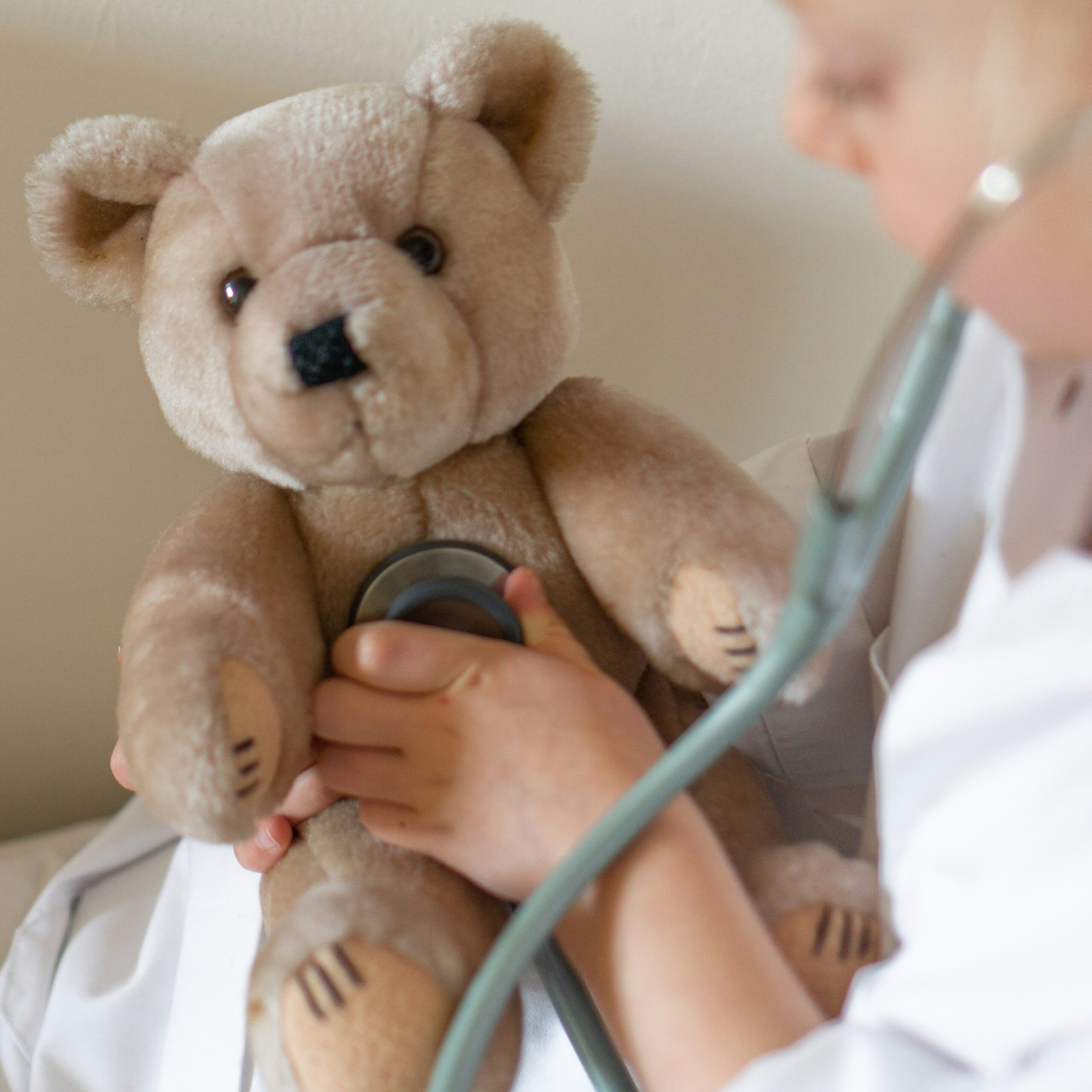 Child pretending to be a doctor checking a teddy bear’s vital signs.