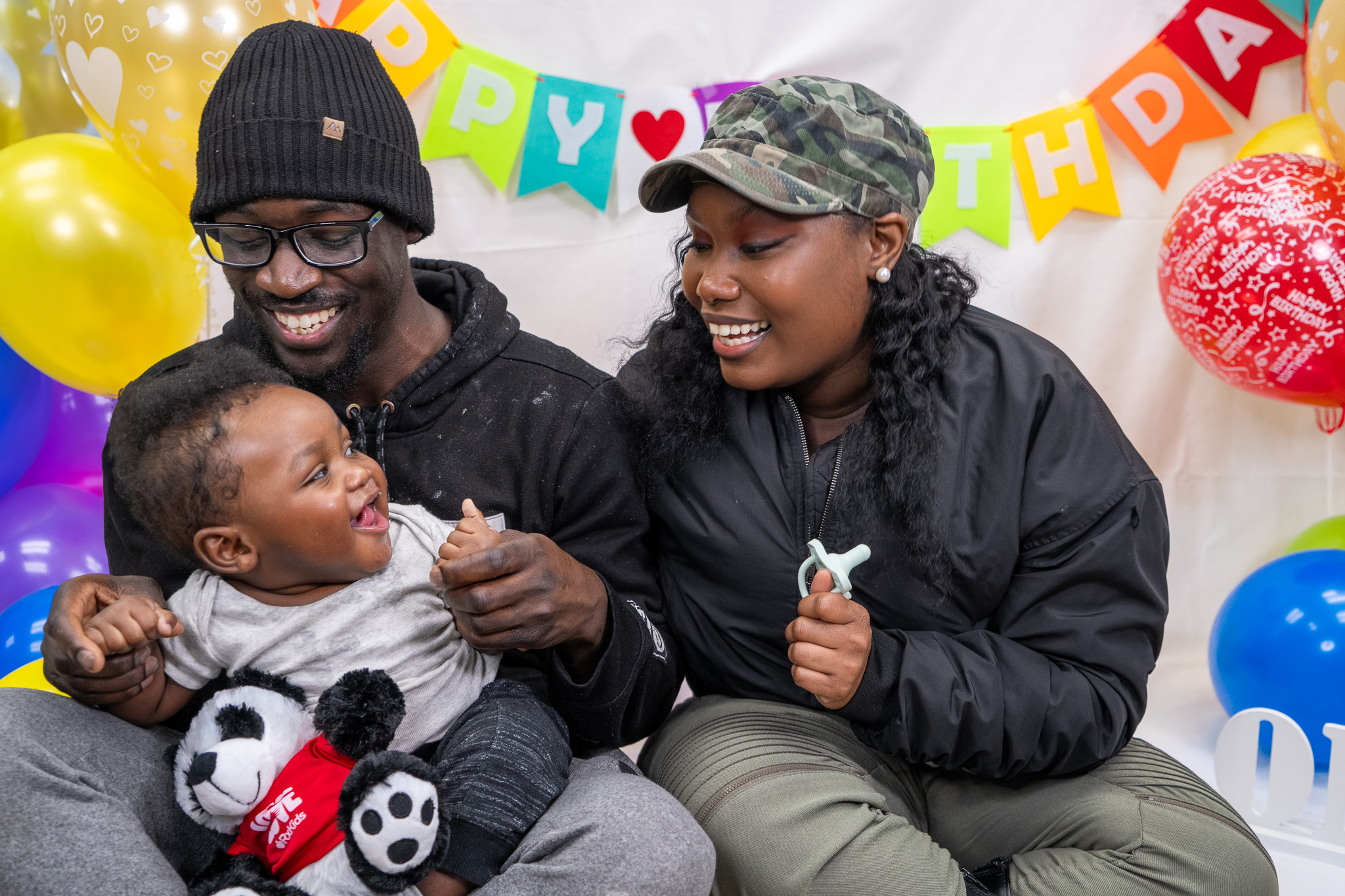 Parents smiling with their baby at a birthday celebration.
