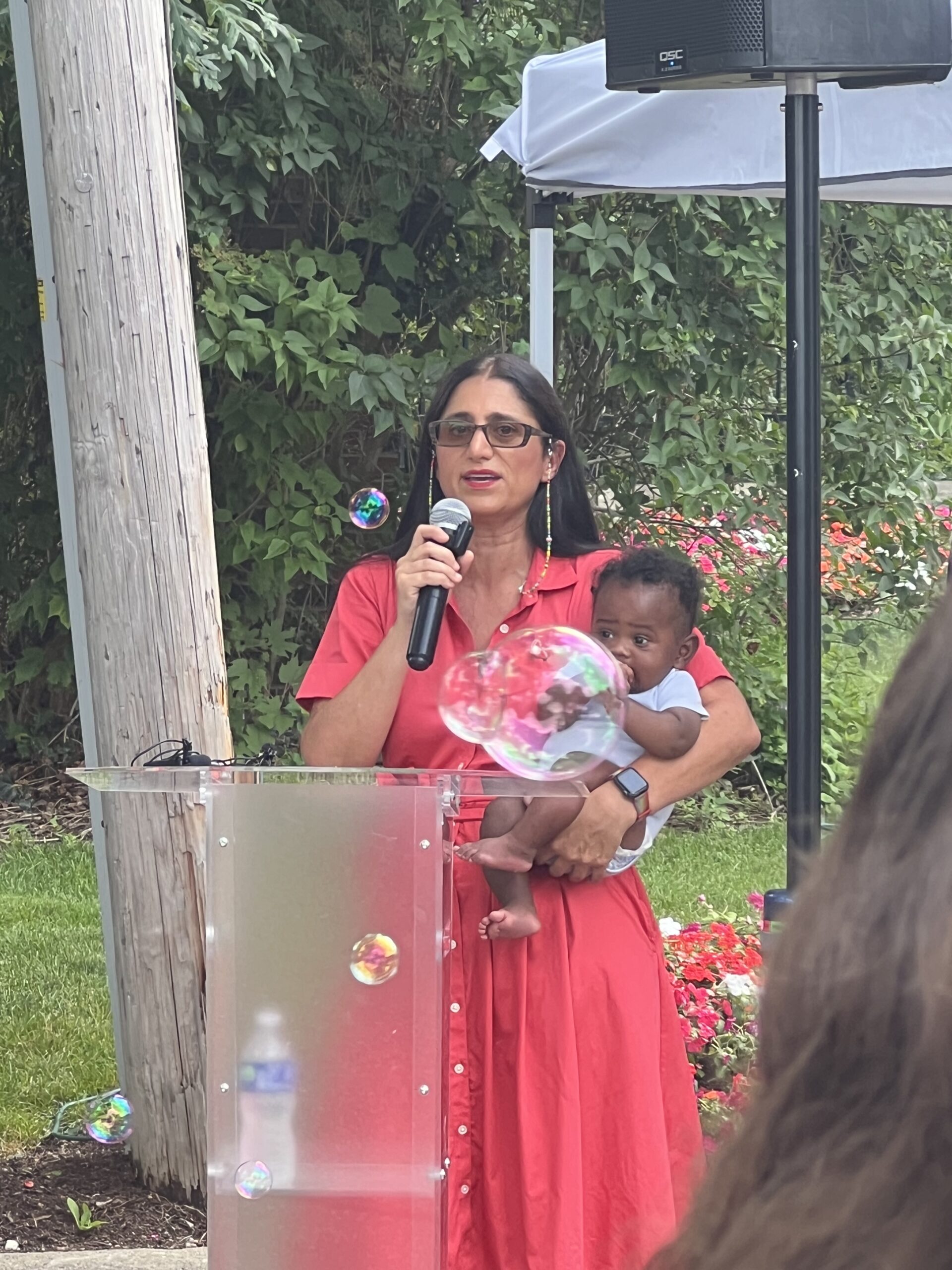 Flint Baby Parade: Dr Mona Hanna-Attisha holding a baby while giving a speech