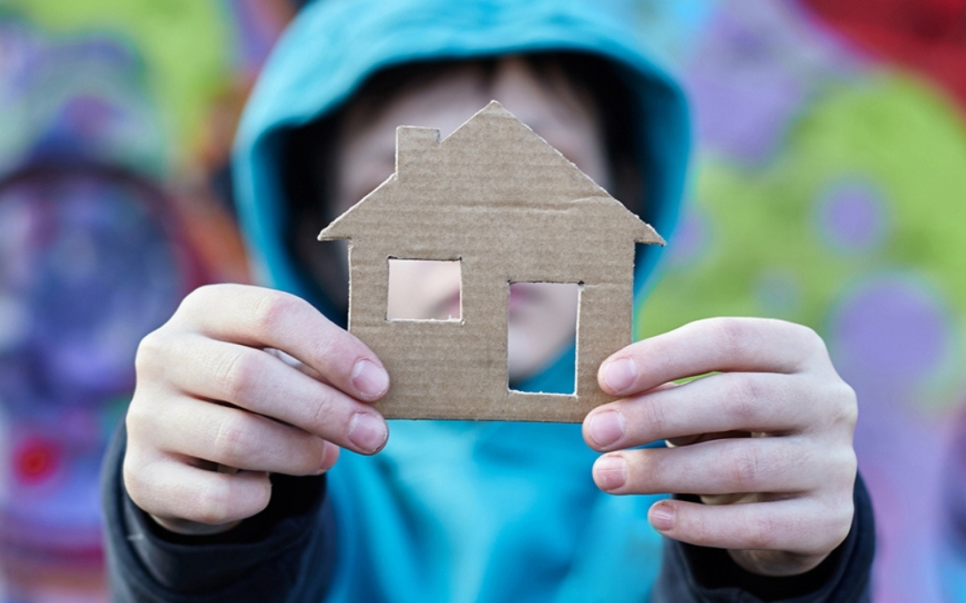 boy holding cardboard cutout of house