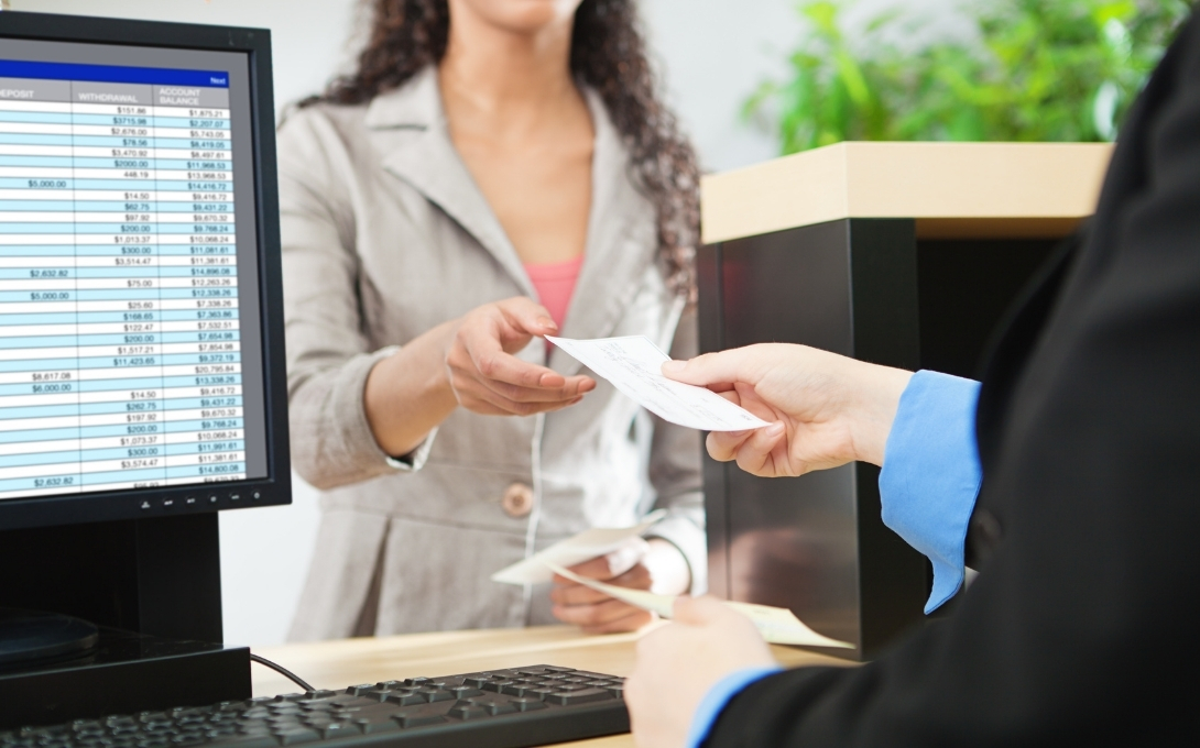 A bank teller hands a person a check