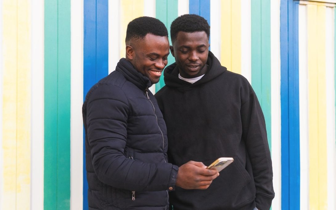 Two Black men look at a phone together