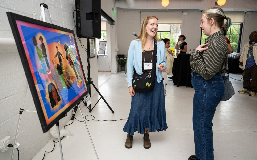 An attendee speaks to a student artist standing near an art piece