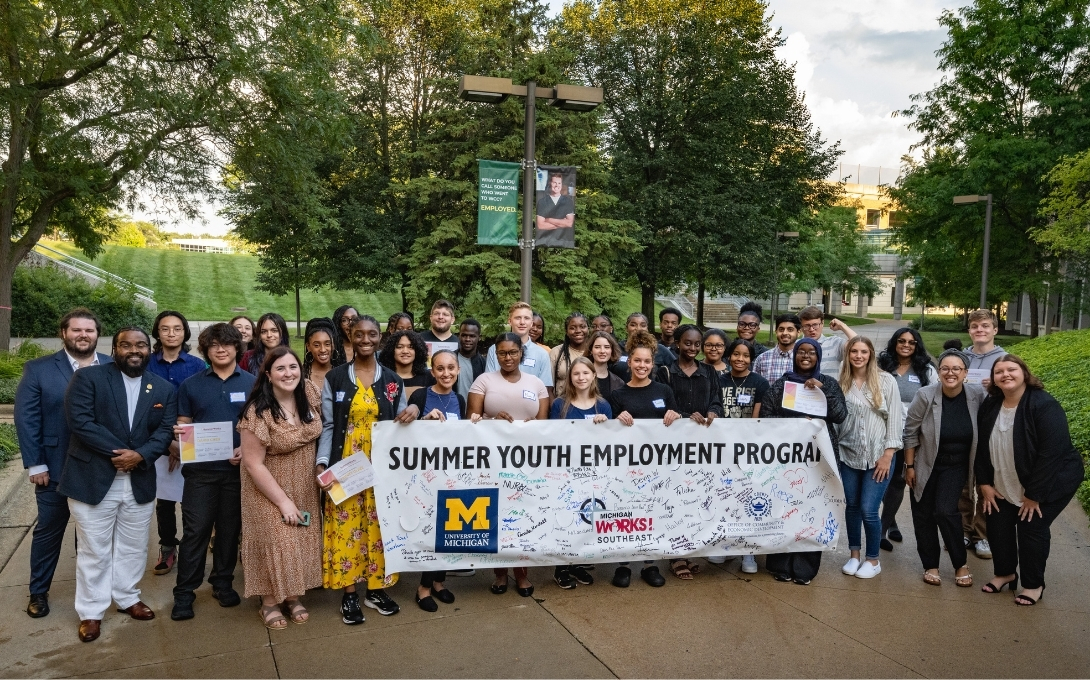 Group photo with a Summer Youth Employment Program banner