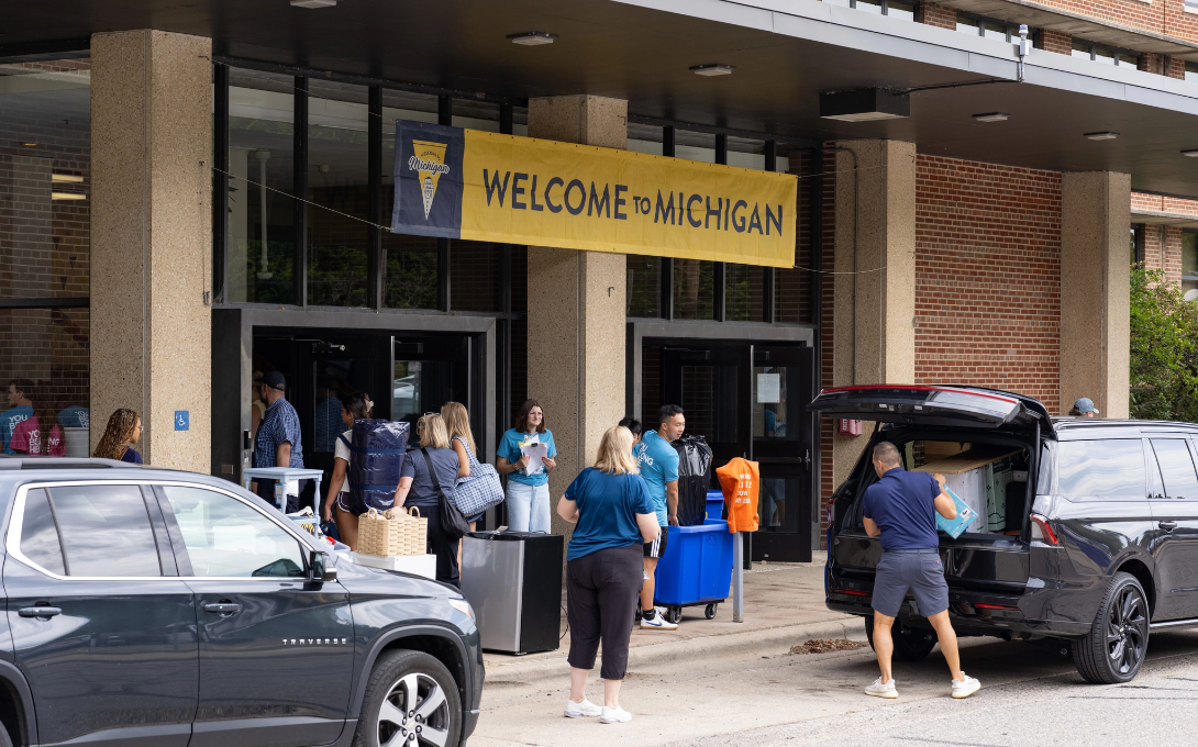 Students and their families unload their vehicles outside a campus building during welcome week